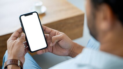 Mockup, woman's hands holding mobile phone with blank screen in coffee shop. Woman using smartphone, looking at the screen, over shoulder view