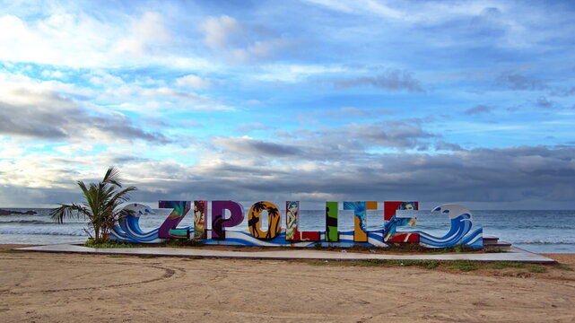 Colorful city sign framed by palm trees on the beach in Zipolite, Mexico