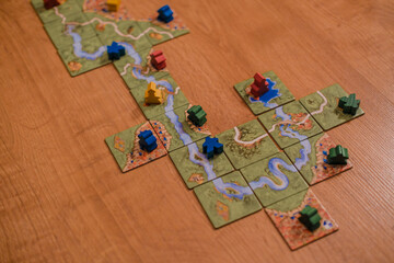A wide view of a Carcassonne board game in progress, with winding river tiles and scattered...