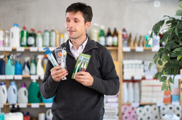 Man looks through product options near open store display. Store visitor chooses toothbrush,...