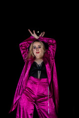 Waacking dancer posing with arms raised in fuchsia outfit at night