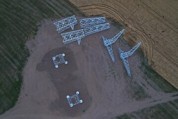High-voltage pylon disassembled on ground with concrete bases before helicopter installation