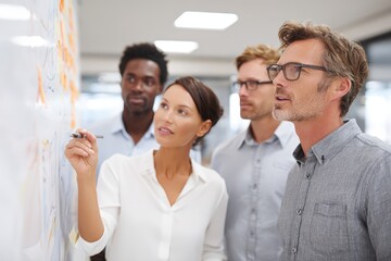 Fototapeta premium Business marketing team engaged in collaborative meeting with graphs and charts, pointing at presentation board in bright office, ideal for innovation strategy and leadership concept visuals