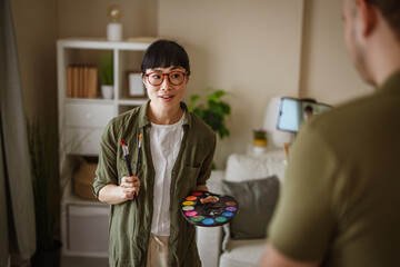 Woman holding palette is recording a video about art