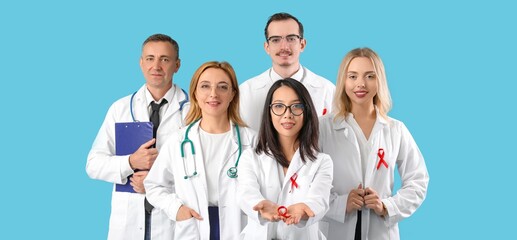 Obraz premium Team of doctors with red ribbons on blue background. HIV AIDS Awareness