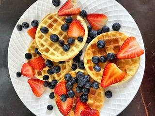 Golden Waffles with Fresh Strawberries and Blueberries on White Plate