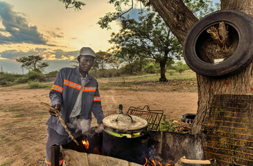 African street vendor, man selling boiled corn on the fire on the side of the road in the village township