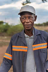 africa village, portrait of single african elderly man, standing on a dirt road,