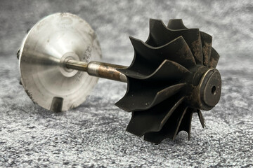 Damaged turbocharger compressor wheels and broken turbine wheel shaft  with black blades from...