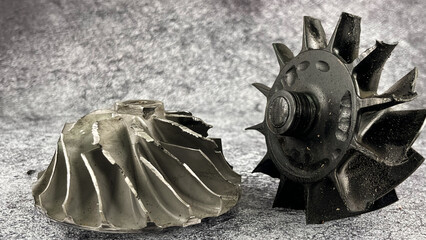 Damaged turbocharger compressor wheels and broken turbine wheel shaft  with black blades from...