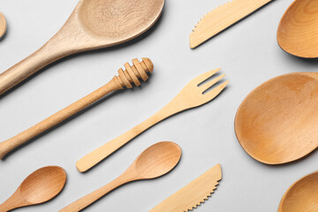 Wooden spoons with forks and knives on grey background