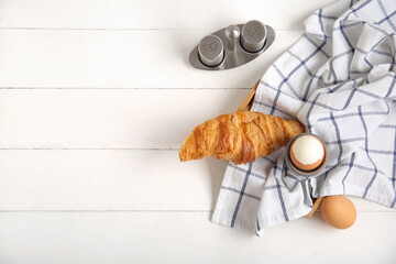 Holder with boiled chicken egg and croissant on white wooden background