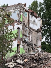 Ruins of an old Soviet apartment building after partial demolition. Exposed brick, debris, and...