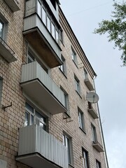Facade of a Soviet-era brick apartment building with multiple balconies and a satellite dish
