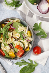 Bowl of tasty pasta salad with pepper and tomatoes on white background
