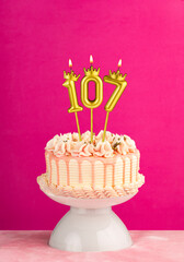 Pink birthday celebration cake with number 107 candle
