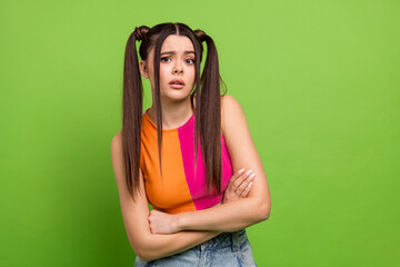 Fashionable young woman with stylish hairstyle in color block top posing against green background...