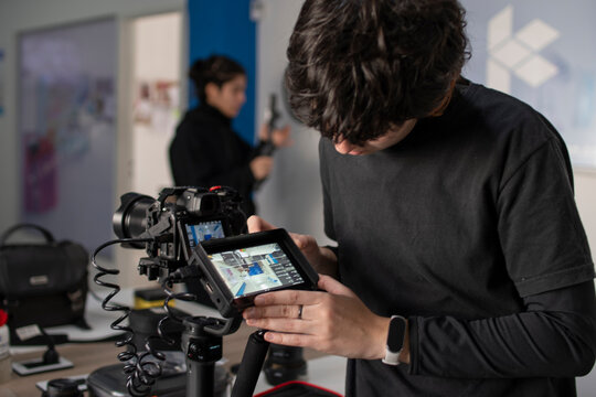 Joven camar&oacute;grafo preparando c&aacute;maras y monitor en gimbal para registro audiovisual video