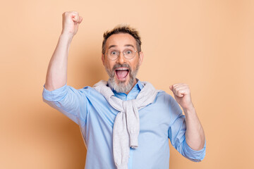 Excited senior businessman celebrating achievement in a joyful pose against beige background