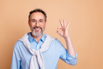 Confident business gentleman making OK gesture with hand on beige background wearing casual...