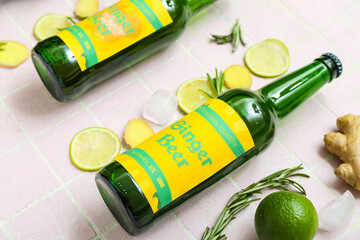 Composition with bottles of fresh ginger beer, rosemary, lime slices and ice cubes on light tile...