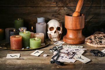 Witch's magic attributes with burning candles on dark wooden table