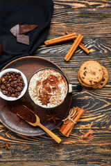 Cup of tasty coffee with cinnamon, beans and cookies on wooden background
