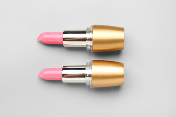 Stylish pink lipsticks on light background