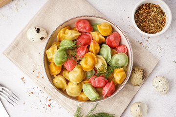 Bowl of boiled colorful dumplings with dill and quail eggs on white background