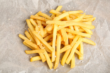 Tasty french fries on parchment, closeup