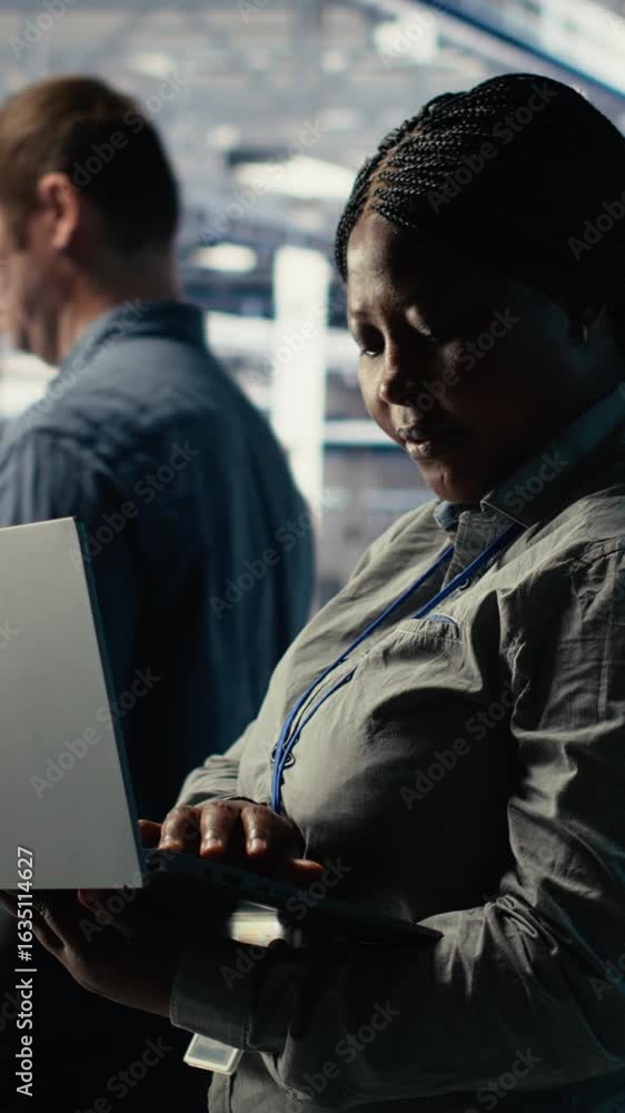 Poster vertical video data center admin monitors deep learning process with laptop, reviewing operational m