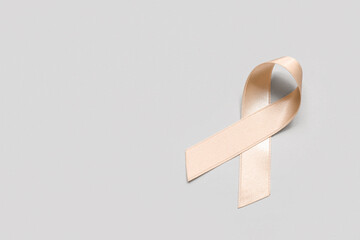 Beige ribbon on light background. Uterine cancer awareness concept