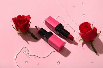 Composition with different lipsticks and beautiful red rose flowers in water on pink background,...