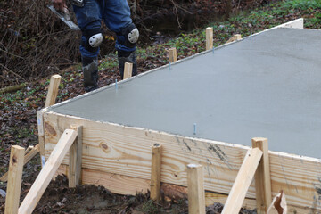 Crew of concrete workers pouring and leveling a shed pad © Robin