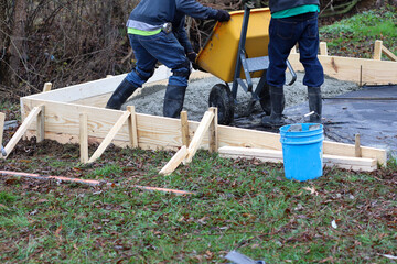 Crew of concrete workers pouring and leveling a shed pad © Robin