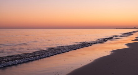Obraz premium Serene Beach Sunset with Gentle Waves and Distant City Silhouette