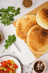 Wooden board of tasty pita bread on white background