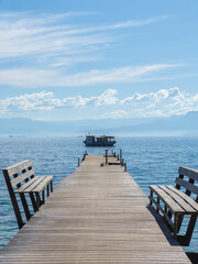 Obraz premium Wooden Pier with Benches and Boat in the Distance in Ilha Grande, Brazil