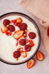Bowl of tasty semolina porridge with fresh berries on white background