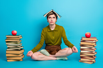 Woman with book meditating with focus and determination in a stylish casual outfit seated against a...