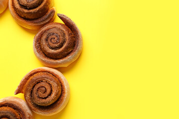 Frame made of tasty cinnamon rolls on yellow background