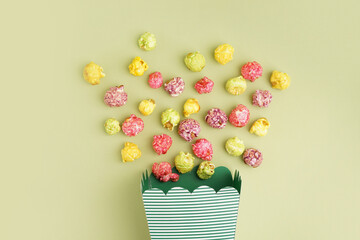 Bucket with sweet colorful popcorn on green background, closeup