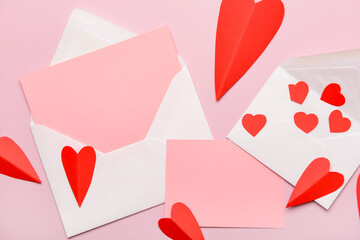 Envelopes with blank cards and red paper hearts on pink background. Valentine's Day celebration