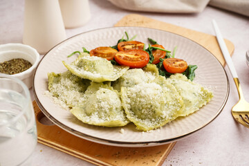 Plate of tasty ravioli with tomatoes and cheese on white background