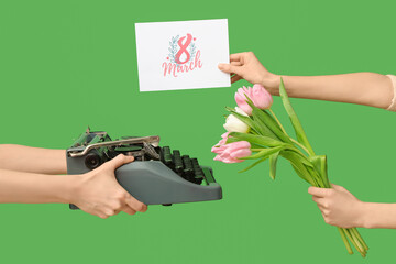 Female hands with retro typewriter, greeting card and tulip flowers for International Women's Day...
