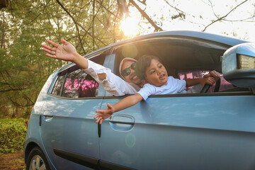 Happy little boy kissing millennial mom in open car window, outdoor in summer, free space....