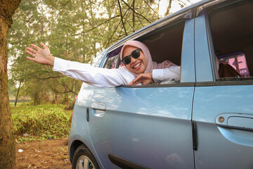 Cheerful pretty millennial middle eastern female in hijab ride in car with driver, looks out open...