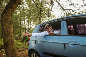 Cheerful pretty millennial middle eastern female in hijab ride in car with driver, looks out open...