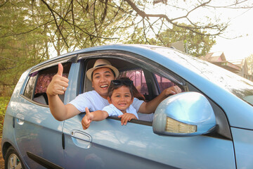 Happy Asian family with father thumb up and mother and son in compact car are smiling and driving...