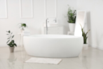 Blurred view of light bathroom with bathtub, sink and plants